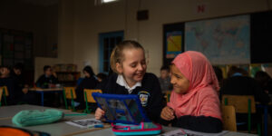 Two young children looking at an ipad in a classroom